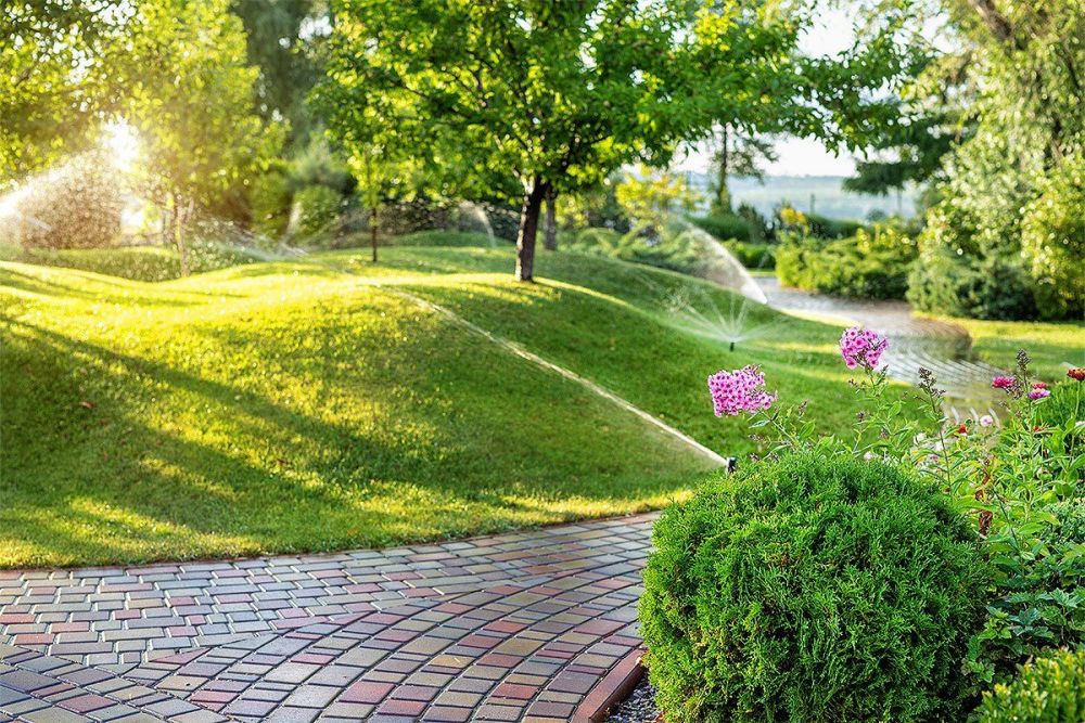 Eine Parkanlage mit Gras überwucherten Hügeln und Bäumen, welche bewässert werden